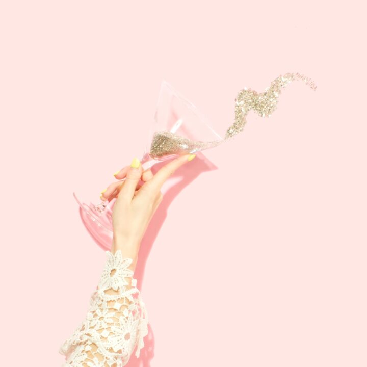 Martini glass spilling glitter on pink background